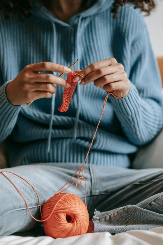 a woman sitting on a couch knitting a ball of yarn, by Jessie Algie, trending on pexels, made of beads and yarn, teenage boy, red and blue garments, programming