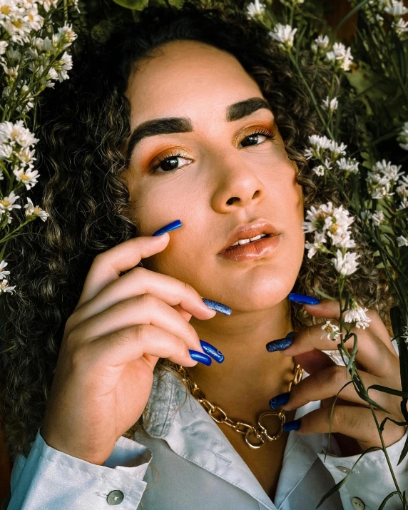 a woman with blue nails is surrounded by flowers, an album cover, trending on pexels, antipodeans, mixed race woman, non binary model, curls and curves, luts