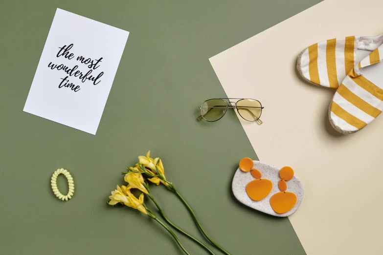 a pair of shoes and some flowers on a table, a still life, inspired by Eden Box, trending on pexels, minimalism, orange sunglasses, yellow gemstones, resin and clay art, background image