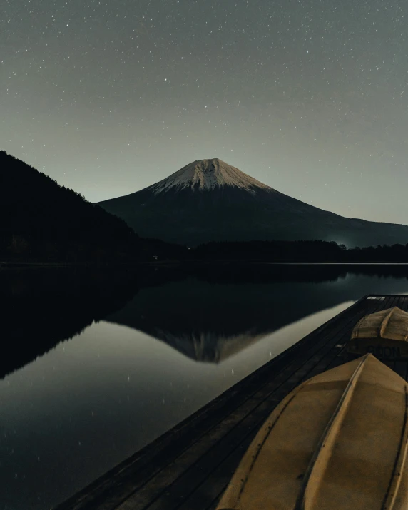 a boat sitting on top of a lake next to a mountain, by Carey Morris, trending on unsplash, ukiyo-e, night time footage, ☁🌪🌙👩🏾, in karuizawa, small canoes