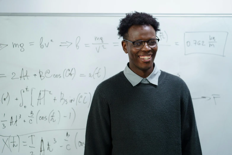 a man standing in front of a white board, adut akech, maths, full frame image, subject is smiling