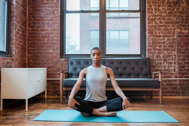 a woman sitting on a yoga mat in a living room, by Nina Hamnett, pexels contest winner, aida muluneh, meditating pose, promo image, city views