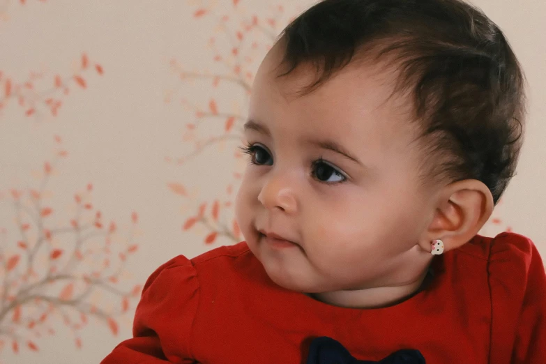 a close up of a baby wearing a red shirt, precious gems, modelling, looking from side, amelie poulain
