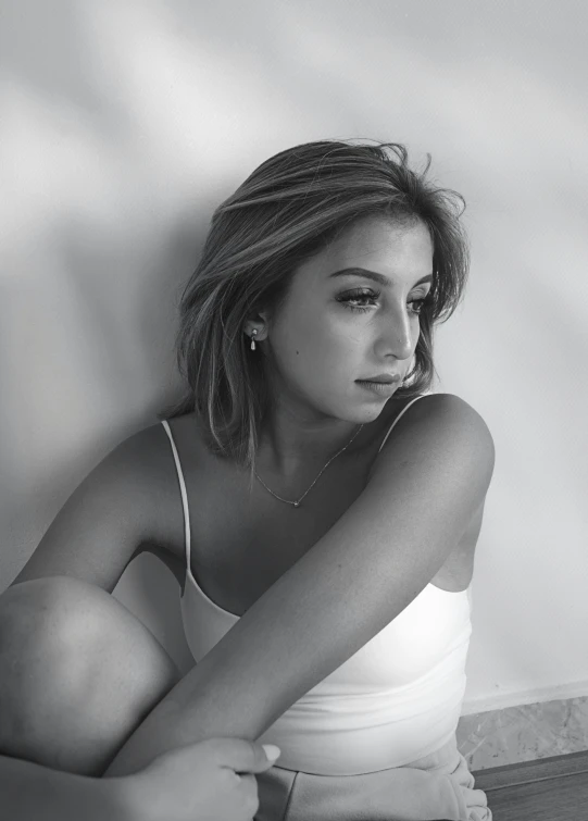 a black and white photo of a woman sitting on a bed, a black and white photo, inspired by Ion Andreescu, trending on pexels, portrait of ariana grande, wearing white camisole, promotional image, ashteroth