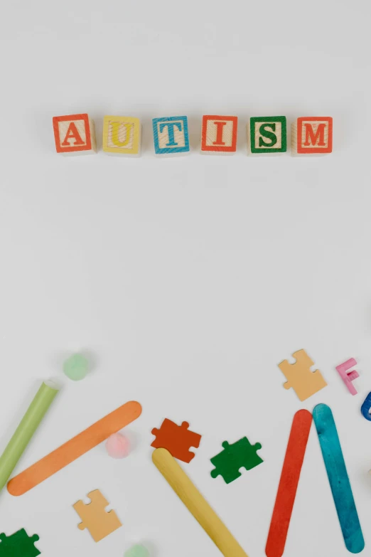 the word autism spelled in wooden letters on a white surface, a child's drawing, trending on pexels, aestheticism, ribbons, legos, light show, subject center bottom of frame