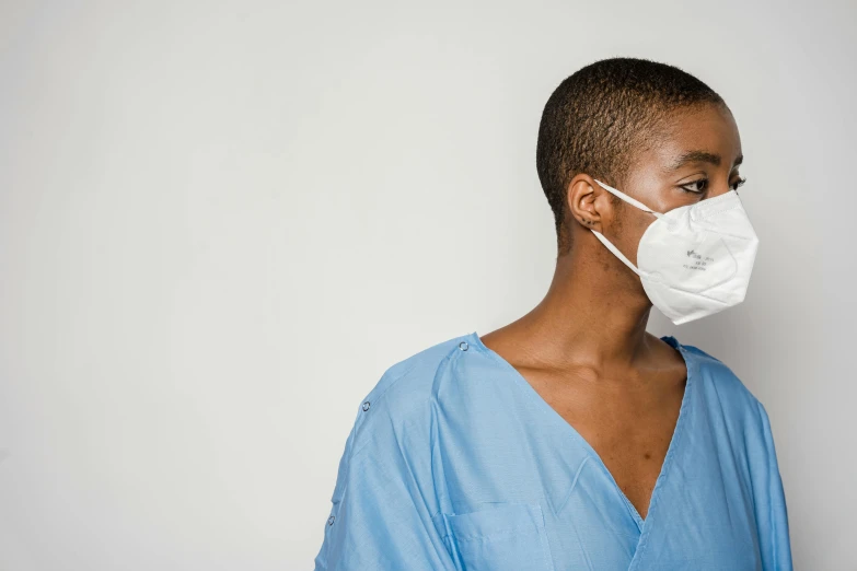 a close up of a person wearing a surgical mask, a photo, by Paul Davis, trending on pexels, happening, nurse uniform, on a pale background, looking to the side, african american