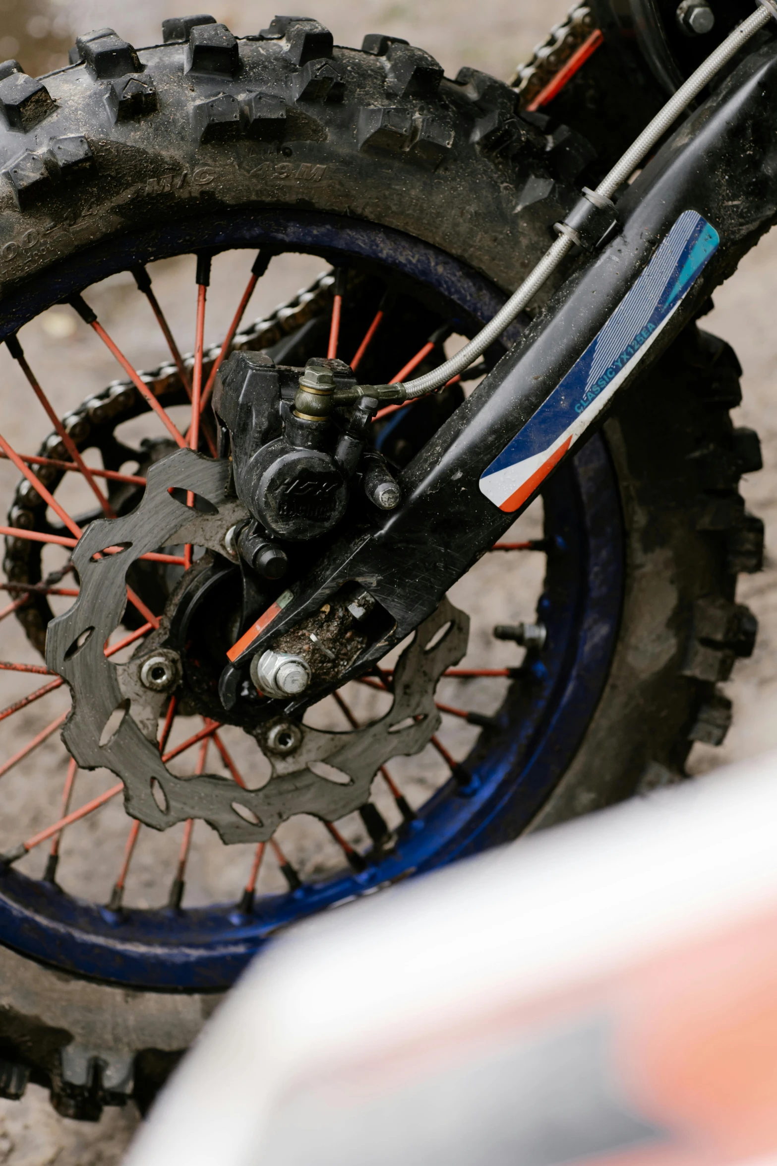 a close up of the front wheel of a dirt bike, blue and orange, vehicle, wheels, off - road