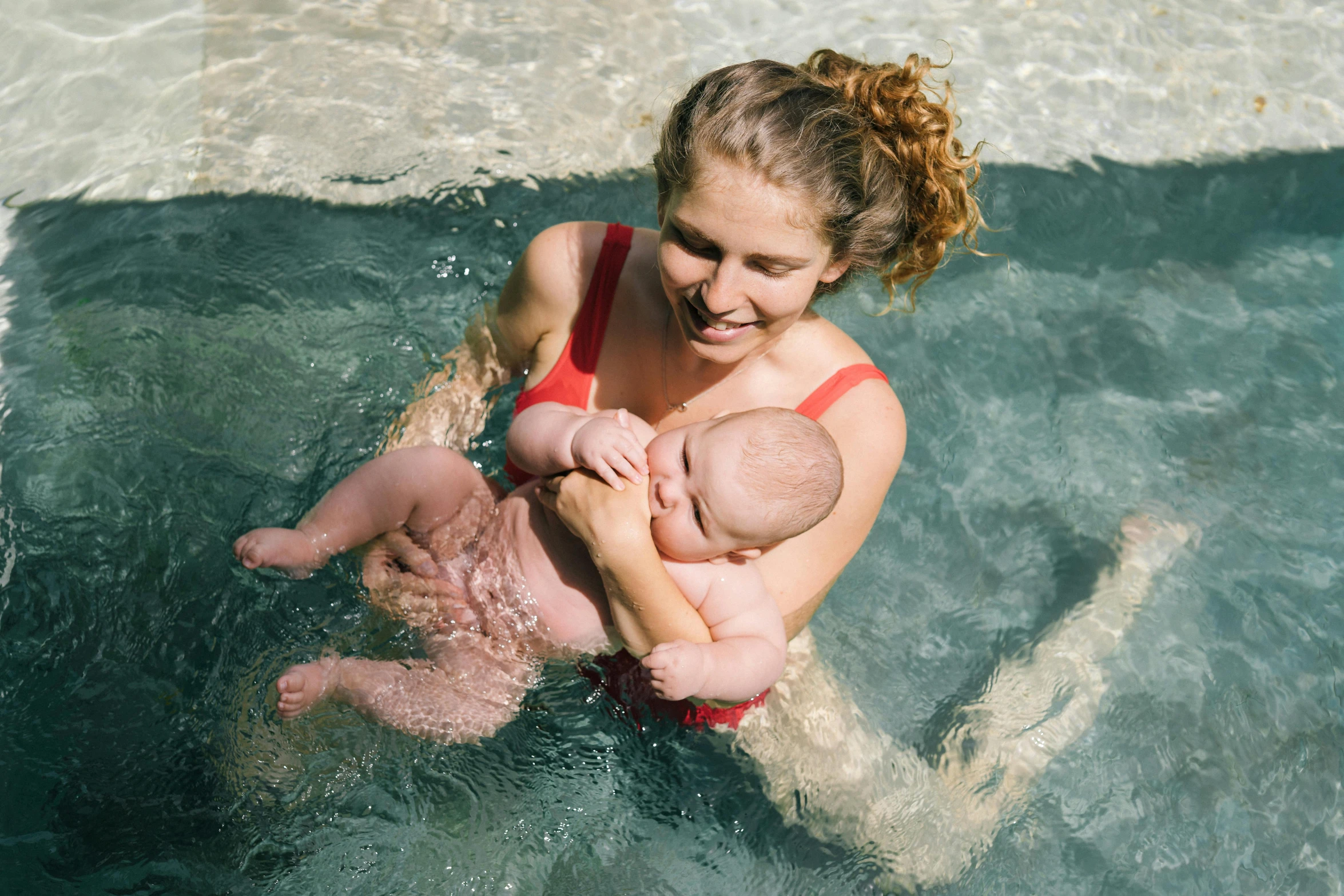 a woman holding a baby in a pool, unsplash, manuka, thumbnail, charli bowater, very high resolution