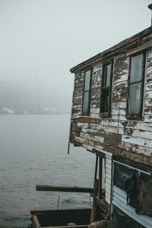 a boat sitting on top of a body of water, old house, hazy and dreary, wooden structures, bay