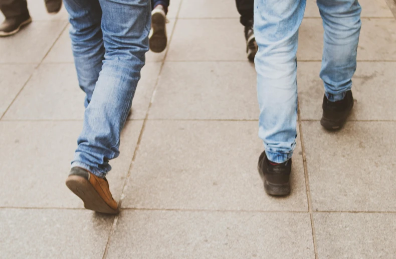 a group of people walking down a sidewalk, trending on pexels, blue jeans, background image, close-up photo