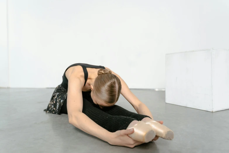 a woman in a black dress is sitting on the floor, inspired by Sarah Lucas, unsplash, ballet, resine figure, pixeled stretching, dezeen