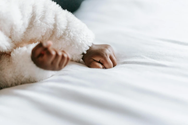 a close up of a person laying on a bed, by Carey Morris, pexels contest winner, symbolism, young child, bump in form of hand, detailed white, crawling