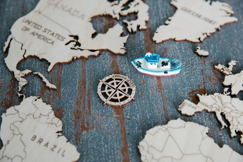 a toy boat sitting on top of a map, bespoke, pins, engraved, blue: 0.5
