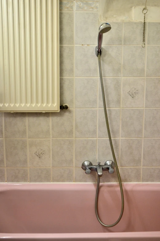 a pink bath tub sitting in a bathroom next to a radiator, inspired by Marcel Duchamp, flickr, detailed moisture, drainpipes, local close up, yellowing wallpaper