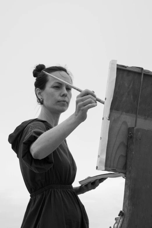 a black and white photo of a woman painting, inspired by Anna Füssli, stålenhag, easel, holding brush, anastasia ovchinnikova