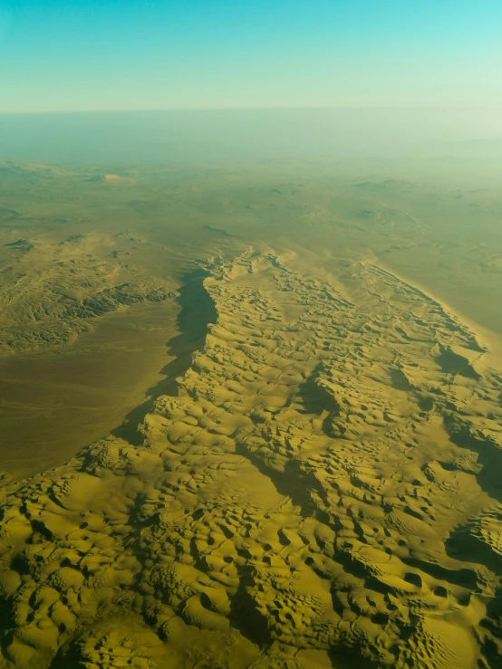 a view of the desert from an airplane, hurufiyya, erosion algorithm landscape, gigantic landscape!, giant crater in distance, coastline