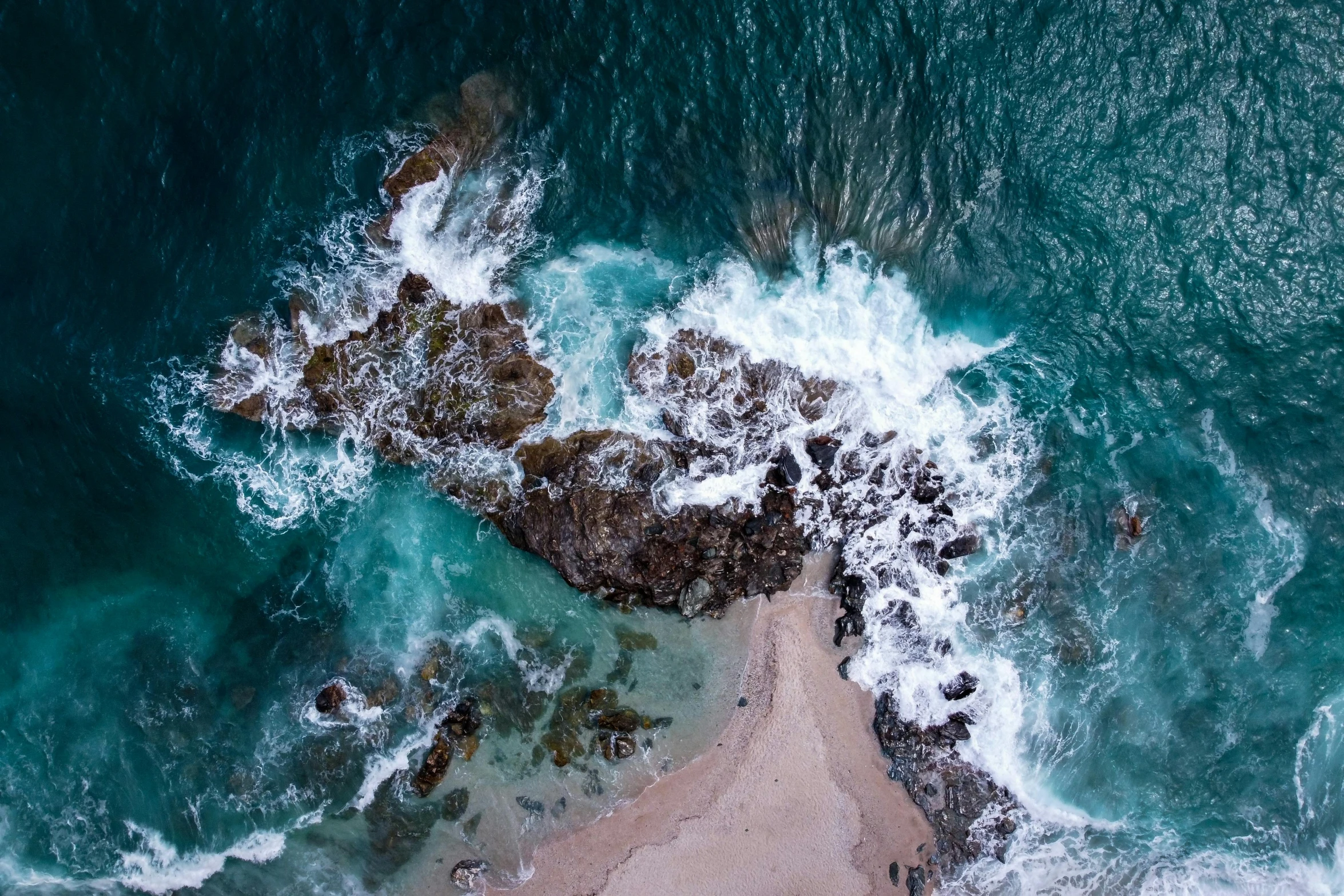 a large body of water next to a sandy beach, by Daniel Lieske, pexels contest winner, mid air shot, ocean spray, rocky coast, down there