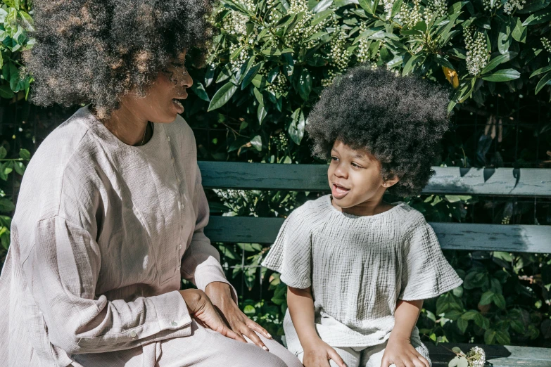 a woman and a child sitting on a bench, pexels contest winner, afro comb, praised, sitting in the garden, black