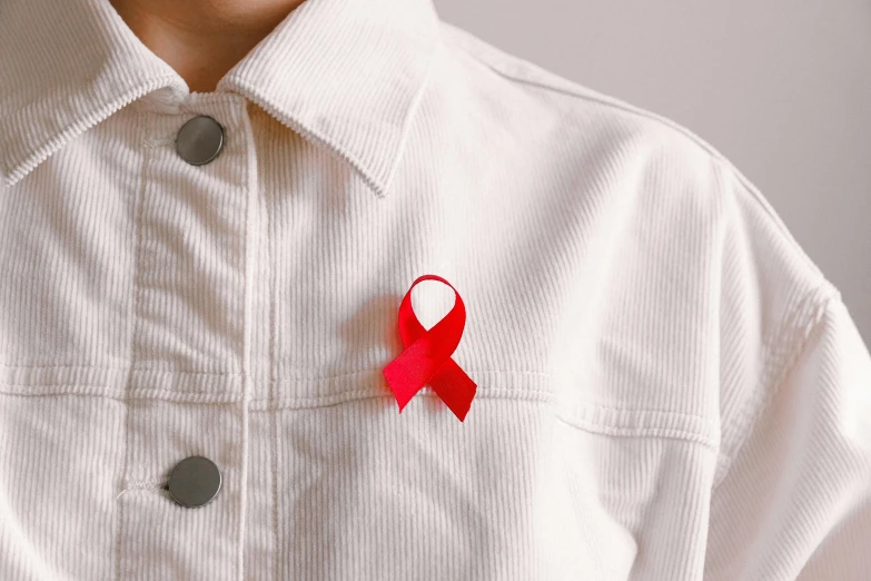 a person wearing a white shirt with a red ribbon on it, trending on pexels, antipodeans, contracept, badge, wearing red, diagnostics
