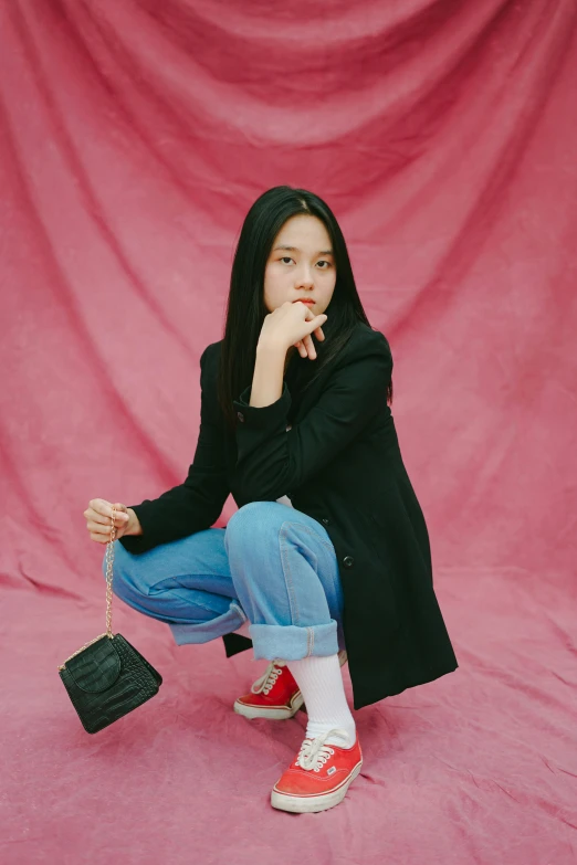 a woman sitting in front of a pink backdrop, wearing jeans and a black hoodie, wei wang, red velvet, girl in a suit