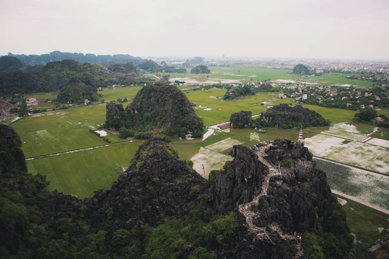 an aerial view of a lush green valley, a picture, happening, vietnamese temple scene, orelsan, looking towards camera, grey
