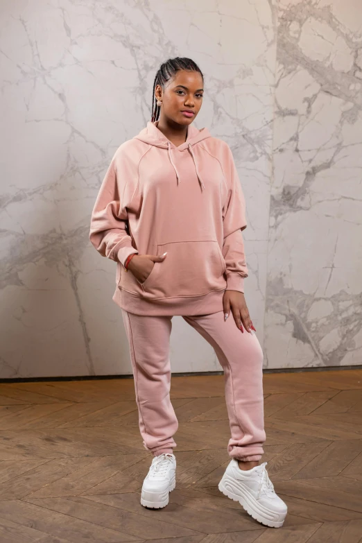 a woman standing in front of a marble wall, by Nina Hamnett, wearing a pink hoodie, full body hero, wearing a tracksuit, plain background