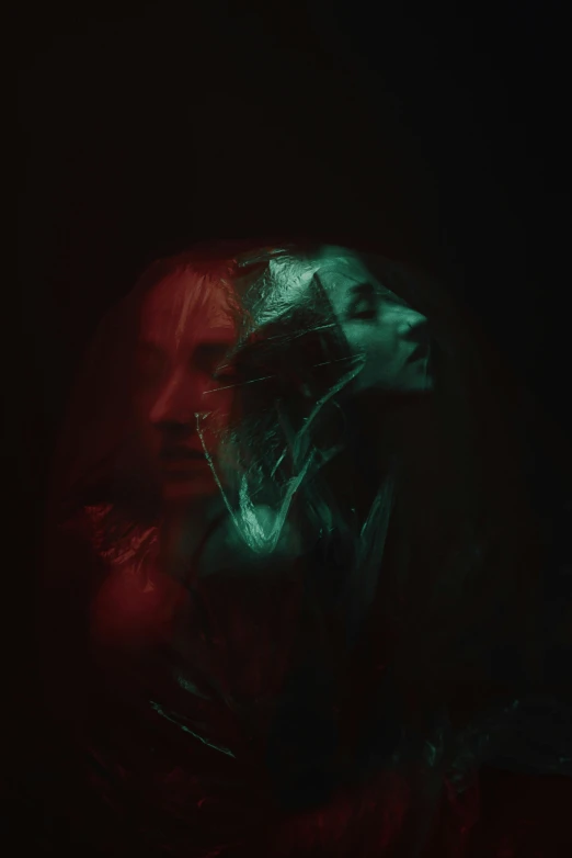 a close up of a person in a dark room, an album cover, inspired by Elsa Bleda, trending on pexels, holography, red green black teal, both faces visible, portrait of a young witch, double - exposure