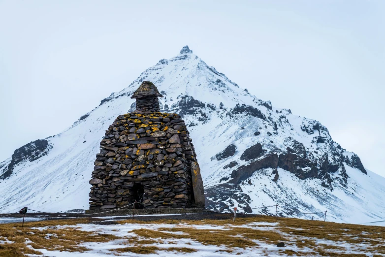 a stone building with a mountain in the background, an album cover, by Jesper Knudsen, unsplash contest winner, land art, background image, andes