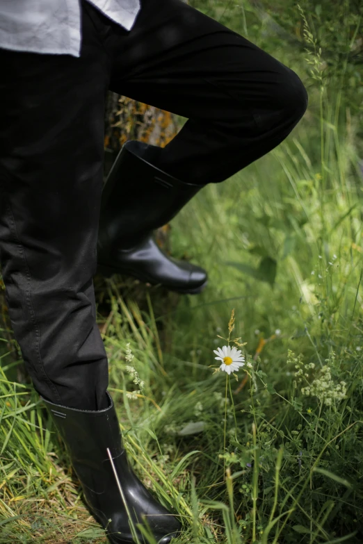 a man that is standing in the grass with a frisbee, inspired by August Sander, unsplash, wearing black boots, detail shot, buttercups, leather pants | natural lighting