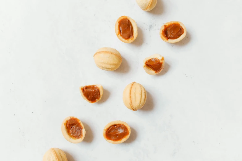 a close up of nuts on a white surface, inspired by Károly Patkó, trending on pexels, hurufiyya, caramel, japanese collection product, press shot, background image