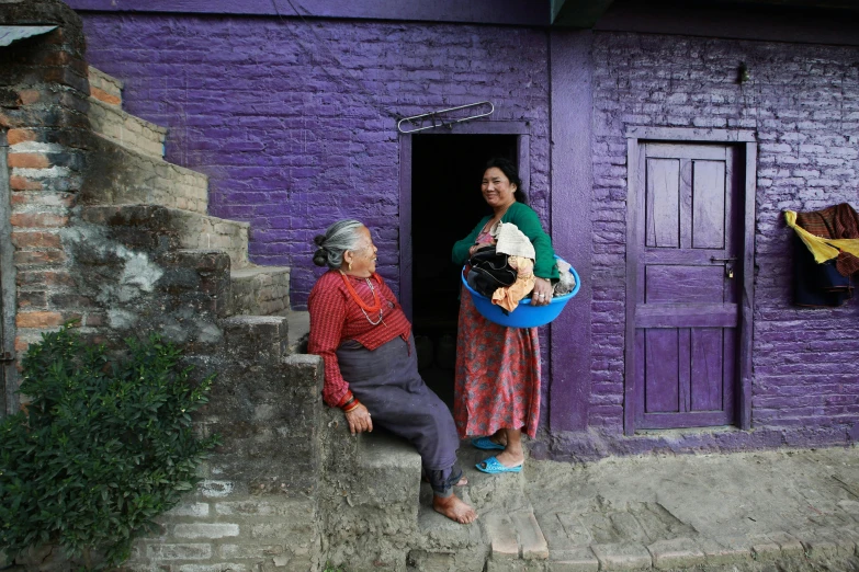 a couple of women standing in front of a purple building, hurufiyya, nepali architecture buildings, slide show, portrait image