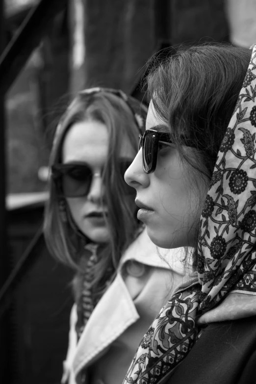 a couple of women standing next to each other, a black and white photo, inspired by Louis Stettner, flickr, photorealism, sunglasses and a scarf, (beautiful) girl, brunettes, hooded