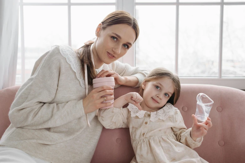 a woman and a little girl sitting on a couch, pexels, realism, milkshake, portrait image, fashion, white