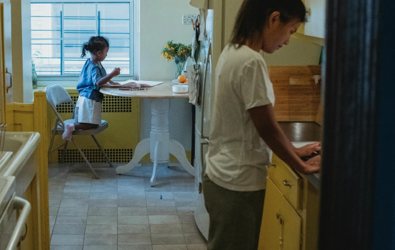 a woman standing in a kitchen next to a child, by William Berra, pexels contest winner, standing on a desk, nanae kawahara, panoramic shot, scene from a movie