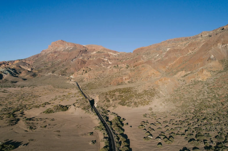 a train traveling through the desert with mountains in the background, unsplash contest winner, land art, red narrow lava rivers, drone photograpghy, central california, chile