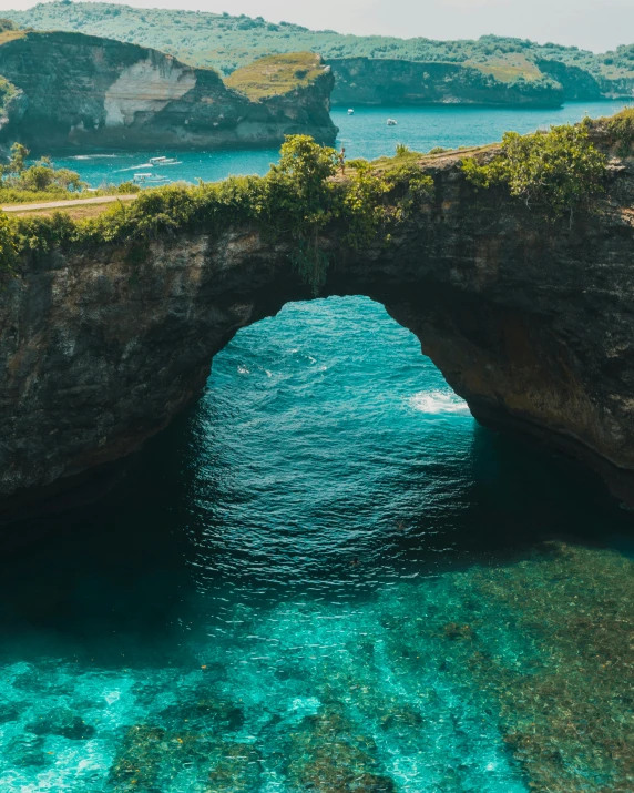 a large body of water with a bridge over it, pexels contest winner, sumatraism, rock arches, thumbnail, teal color graded, bali