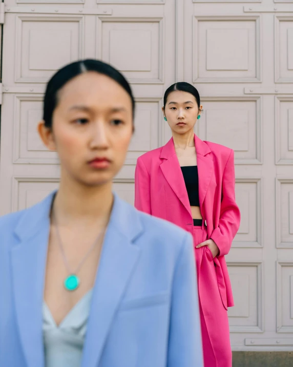 two women standing in front of a garage door, inspired by Ren Hang, trending on pexels, wearing a colorful men's suit, young asian woman, looking serious, cropped shirt with jacket