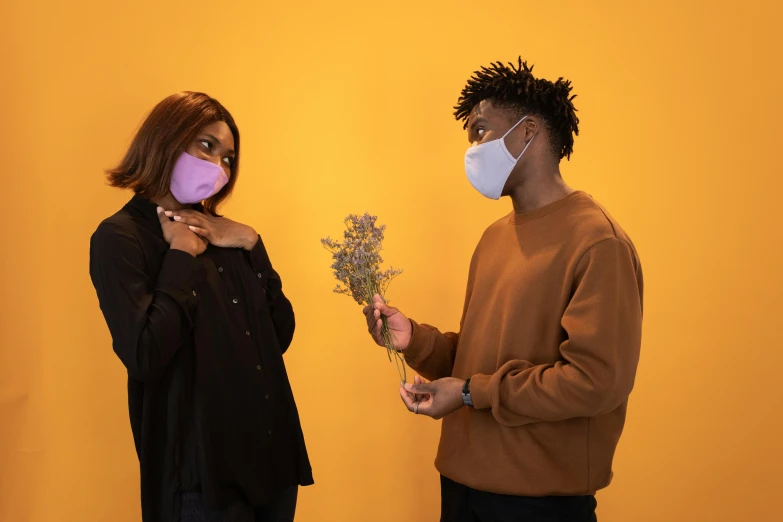 a man and a woman standing next to each other, trending on pexels, romanticism, flower mask, yellow purple, medical mask, ( ( dark skin ) )