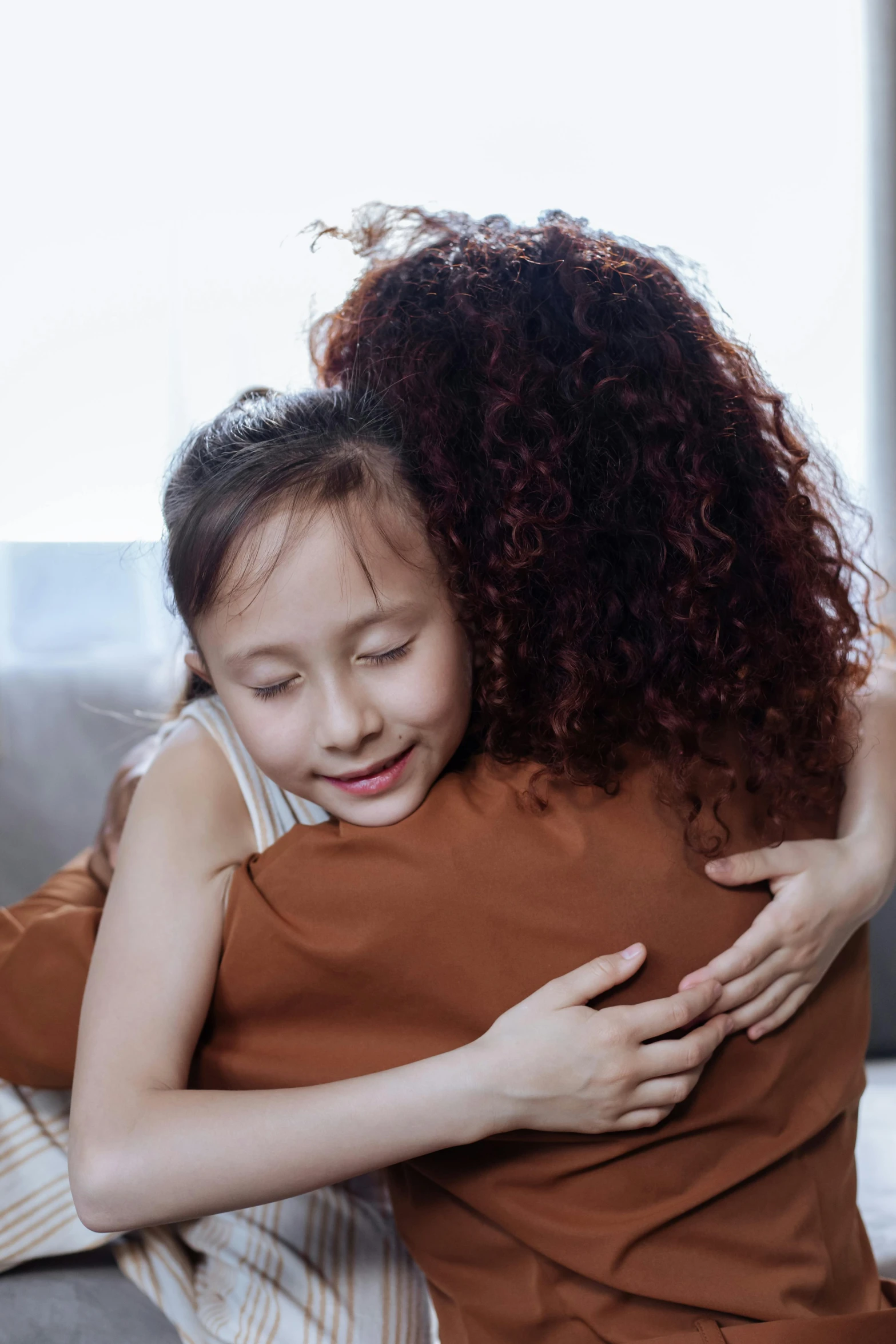 a little girl hugging her mother on the couch, pexels contest winner, incoherents, brown curly hair, a young asian woman, promo image, supportive