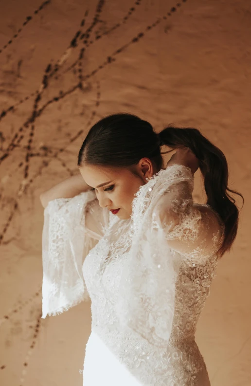 a woman standing in front of a wall wearing a white dress, a portrait, by Robbie Trevino, unsplash, baroque, desert robe, 15081959 21121991 01012000 4k, with a ponytail, in wedding dresses