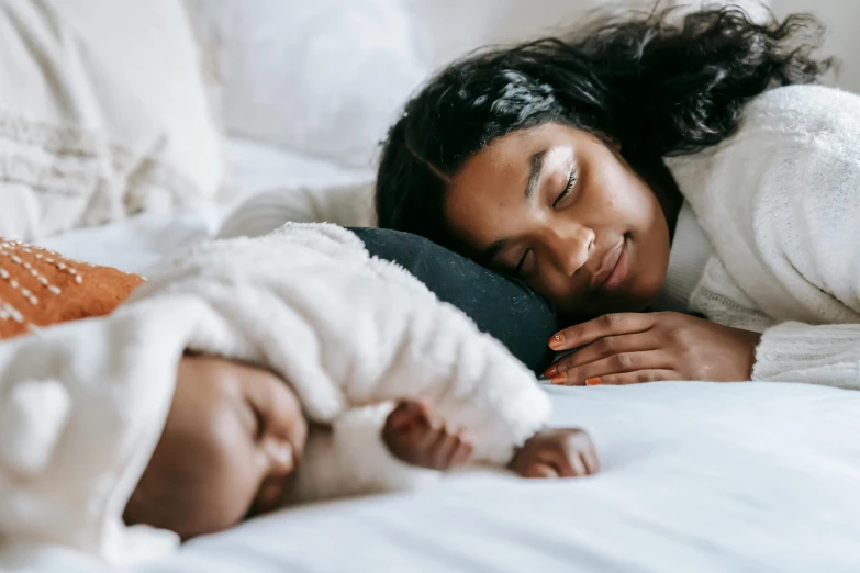 a woman laying on top of a bed next to a baby, pexels contest winner, symbolism, manuka, profile image, closing eyes, 1 4 9 3