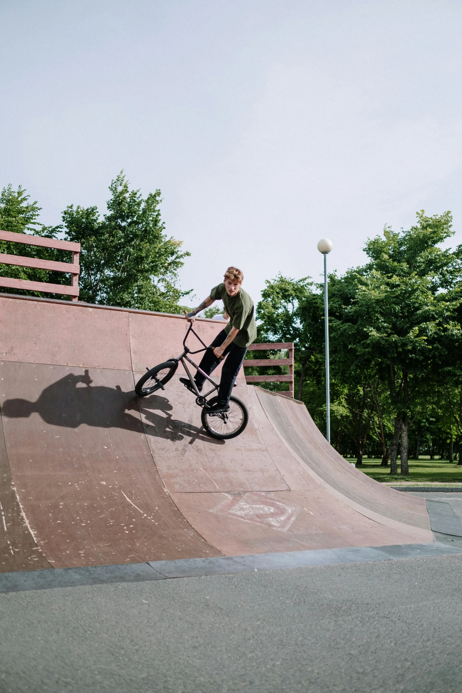 a man riding a bike up the side of a ramp, a picture, in a park, kailee mandel, circle pit, minn