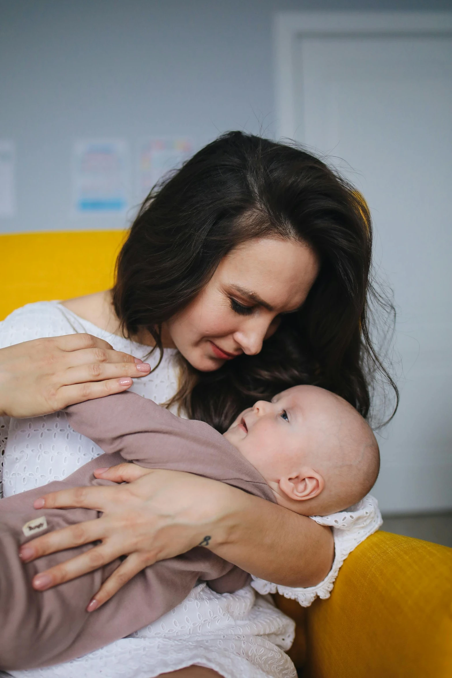 a woman holding a baby in her arms, by Adam Marczyński, pexels, incoherents, resting on chest, brunette, anna nikonova aka newmilky, high quality image