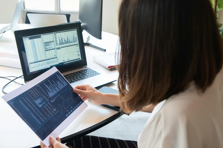 a woman sitting in front of a laptop computer, a picture, trending on unsplash, analytical art, maths, technical document, grey, trading stocks