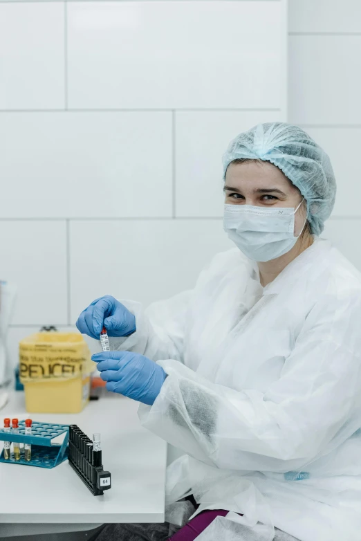 a woman sitting at a table in a lab, a picture, yellow latex gloves, wearing nanotech honeycomb robe, candy treatments, kek