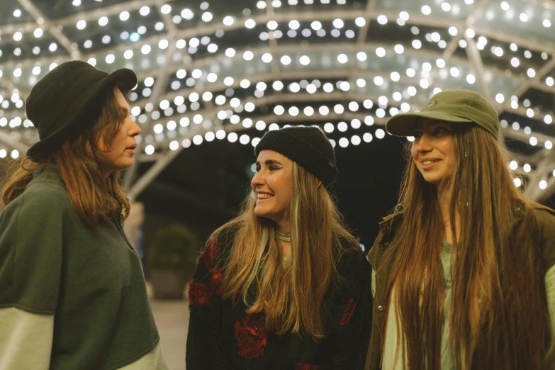 a group of young women standing next to each other, by Emma Andijewska, unsplash contest winner, happening, string lights, wearing a baseball cap, looking to the side off camera, three women