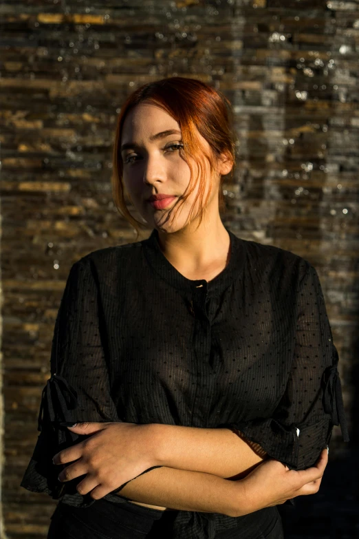 a woman standing in front of a brick wall, a portrait, inspired by Elsa Bleda, unsplash, copper hair, wearing a black shirt, portrait of ana de armas, square