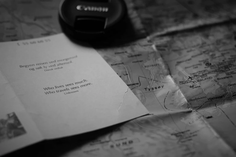 a piece of paper sitting on top of a map, a black and white photo, by Caro Niederer, unsplash, writings, camera, tyler west, lost series