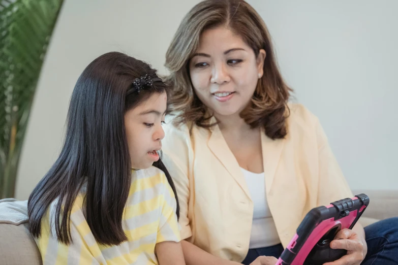 a woman sitting next to a little girl on a couch, by Natasha Tan, pexels contest winner, draw with wacom tablet, teacher, leni robredo, closeup - view