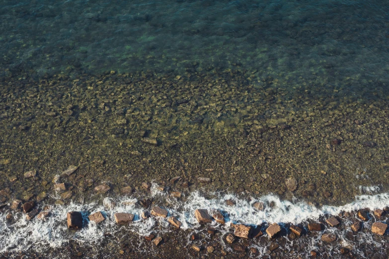 a large body of water next to a rocky shore, inspired by Andreas Gursky, pexels, realism, top down photo, realistic textures, color ( sony a 7 r iv, detail shot